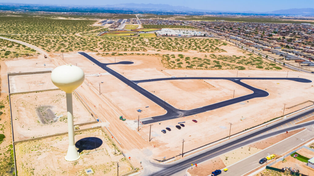 Aerial view of a developing subdivision with paved roads and a water tower.